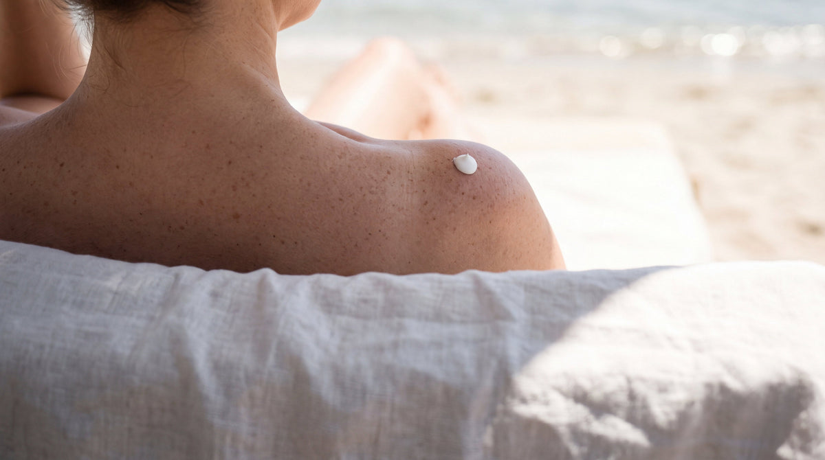 A shoulder in the shade of a linen beach umbrella with a dot of sunscreen, protecting your tattoo from the sun