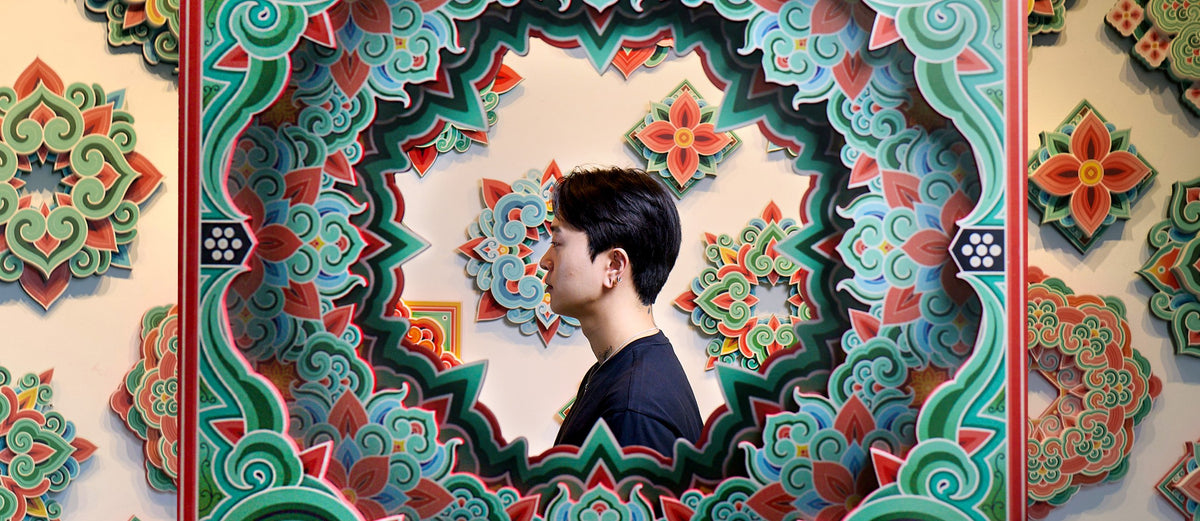 PittaKKM in profile, framed by one of his large dancheong panels in red, green and teal