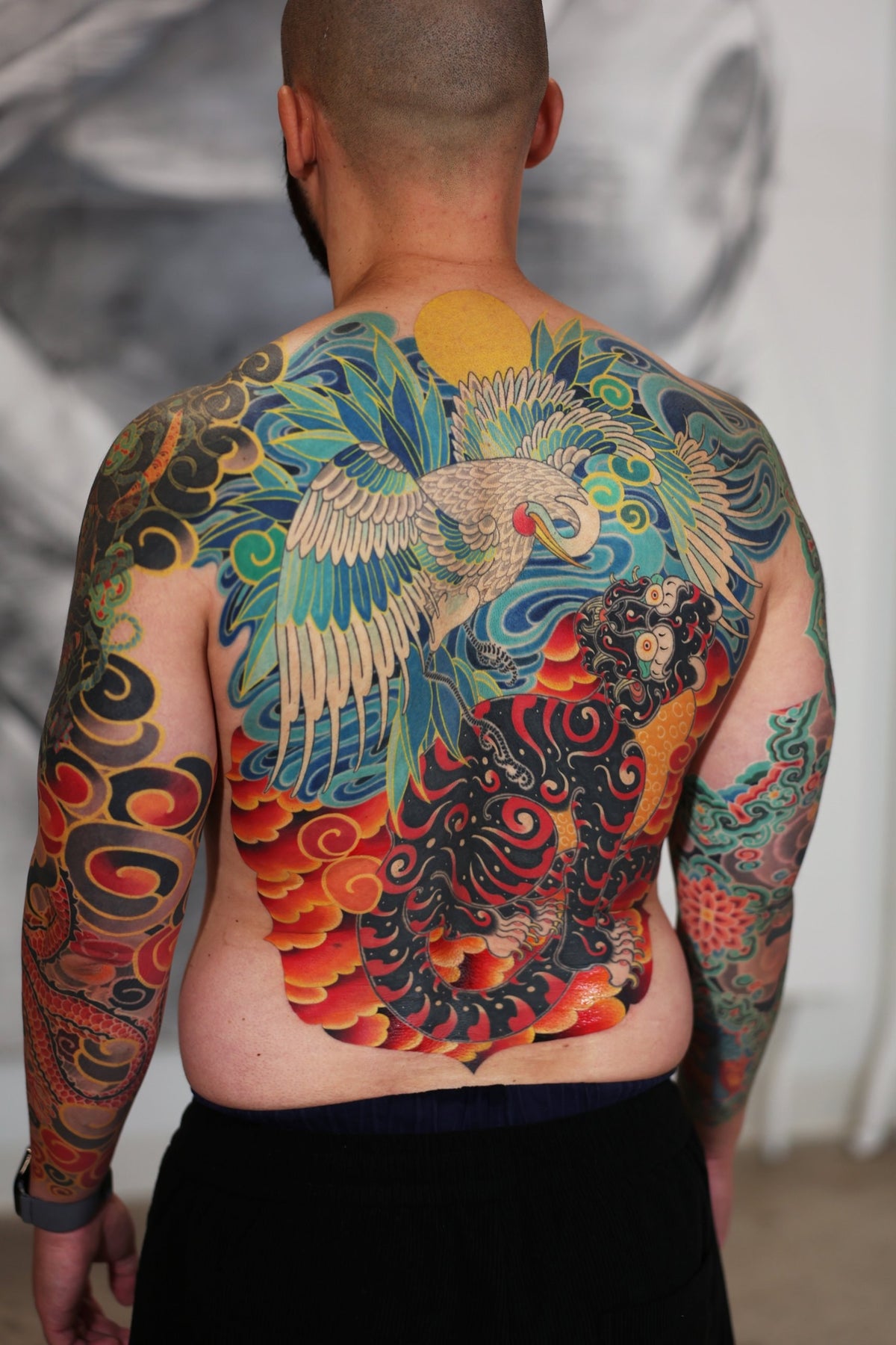 PittaKKM full back tattoo, a white crane descending over a black tiger wreathed in flame cloud under a yellow sun