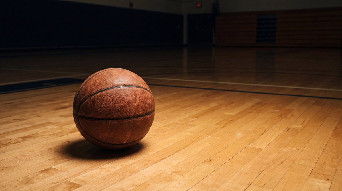 A worn leather basketball alone on an empty court at night, the NBA and tattoos