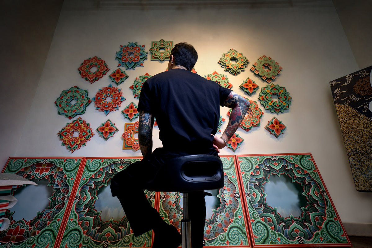 PittaKKM, seen from behind, looking at a wall of his dancheong panels in Korea's 5 sacred colours