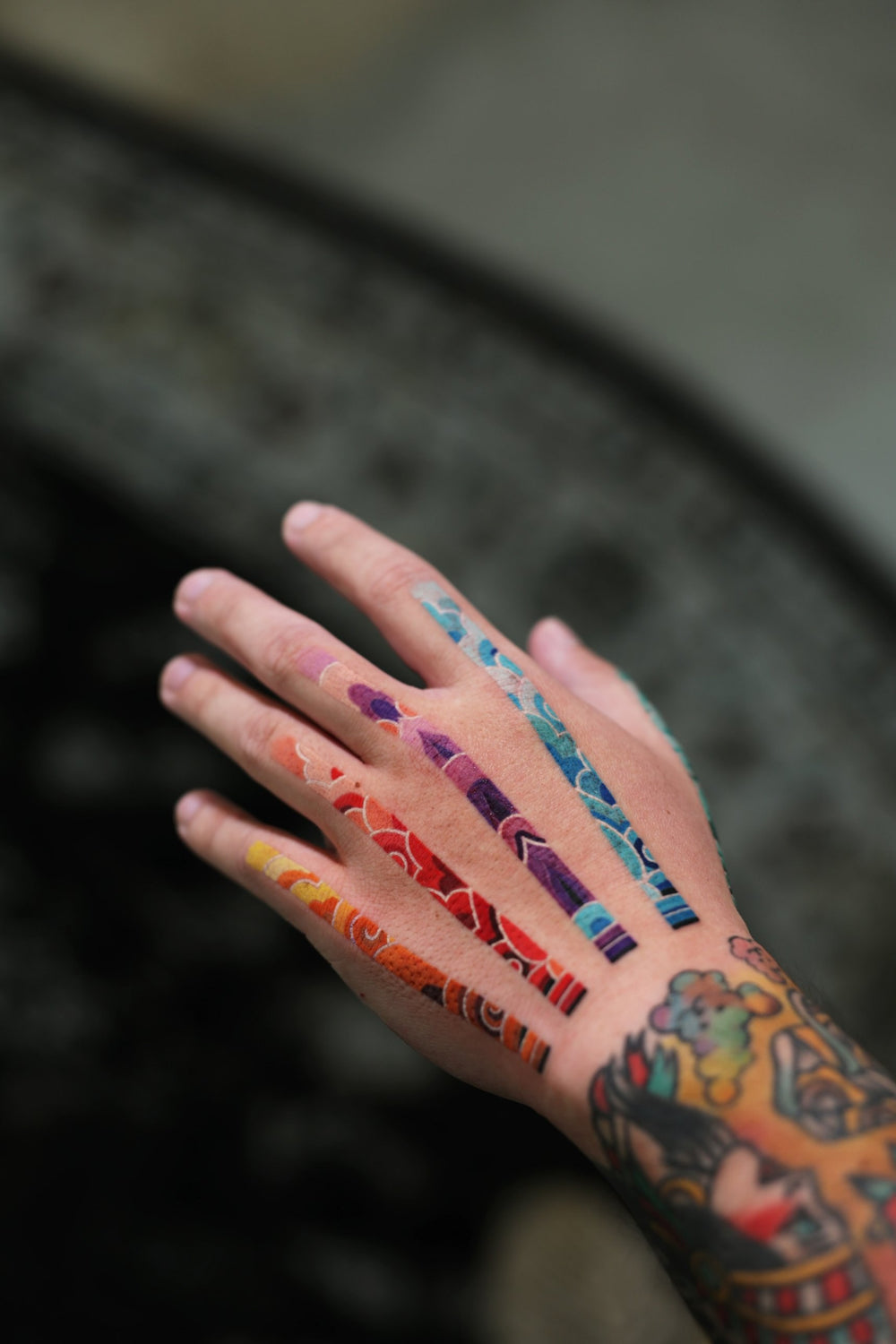 PittaKKM hand tattoo, 4 narrow strips of pattern along the tendons, each finger in its own colour