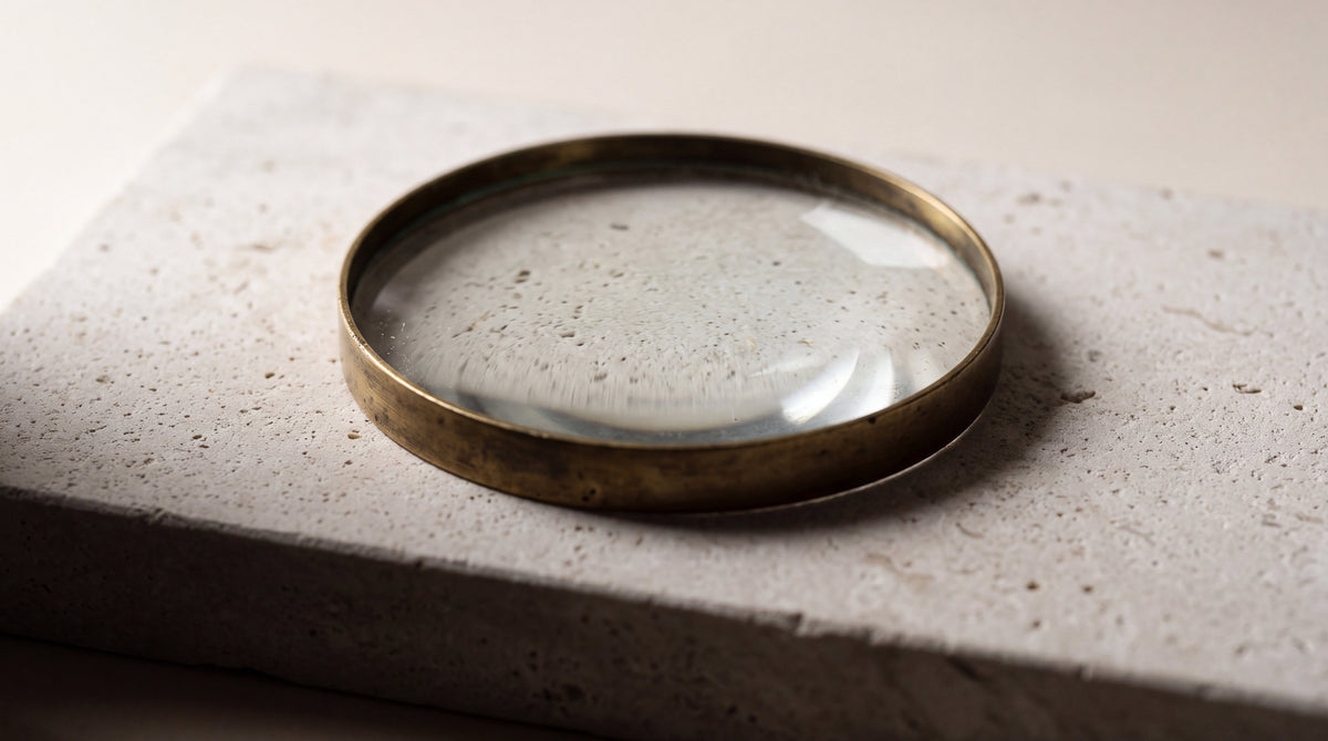 A brass magnifying lens on pale limestone, answers to common tattoo care questions